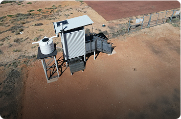 High-angle view of a quick-deploy single-cubicle defence toilet facility positioned on an airfield.