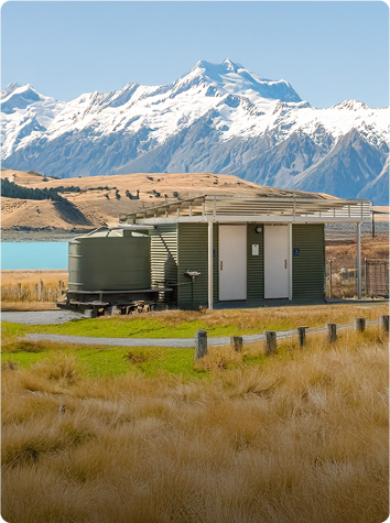 National park public toilet facility in a scenic setting with mountains and a lake in the background.