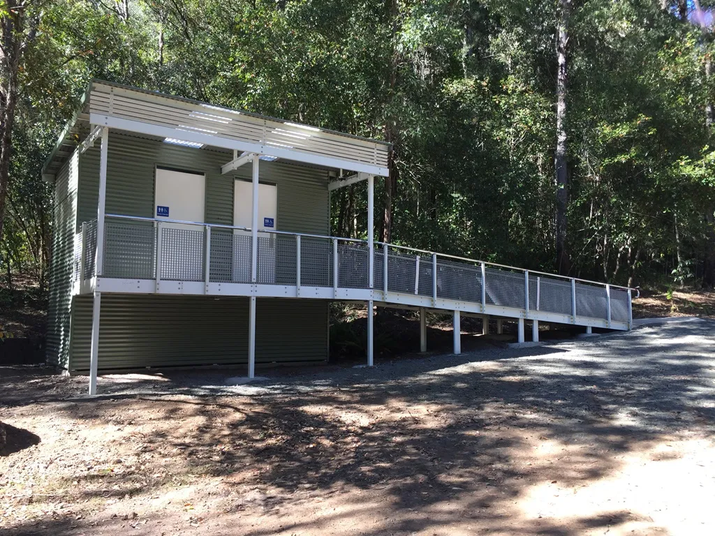 Bells Bay campground toilet—two accessible cubicles on a sloped site with slight ramp gradient; composting system beneath.