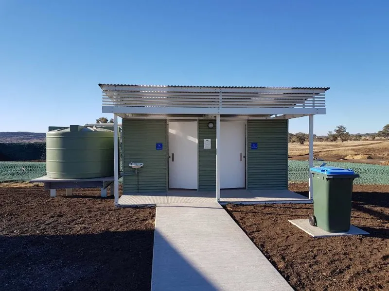 Close-up of Toowoomba truck stop toilet facility showing two cubicles, exterior water tank, and outside handbasin.