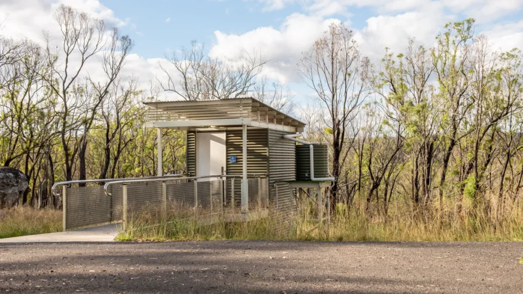 Accessible toilet cubicle on a sloped bush site with level access provided by a straight bridge/boardwalk.