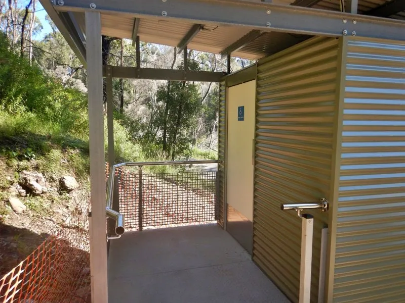 Close-up of the Wonboyn toilet amenity entrance door at Myrtle Cove, showing handle, signage, and cladding detail.