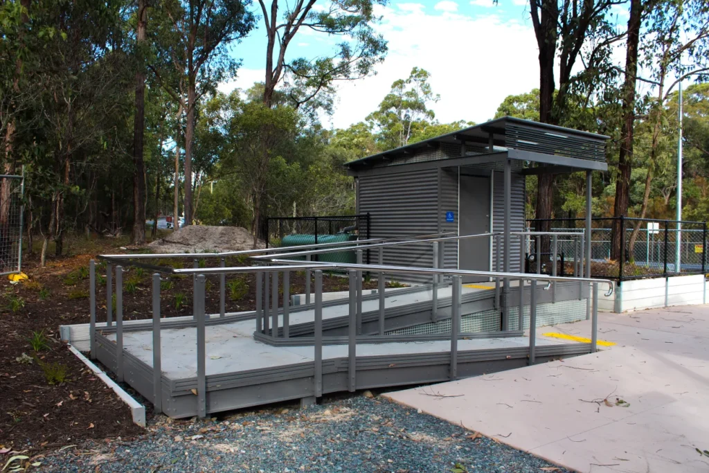 LooCube™ accessible toilet building with wide doorway and ramp with handrails, designed for inclusive access in Aotearoa.